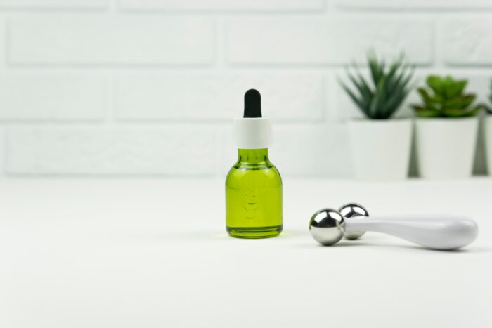 A CBD green oil and a face roller stand on a white table