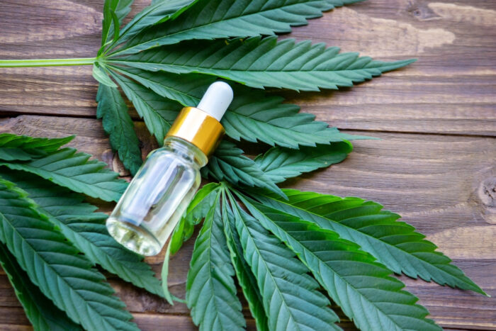 cannabis leaves on wood background with bottles, cannabis oil.