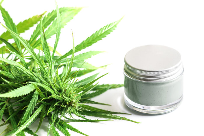 Green cannabis plant and jar with a moisturizing cream